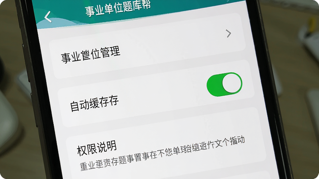 一张展示事业单位题库帮新手设置界面的图片,主体为手机屏幕显示设置选项列表,布局上方是缓存管理,中间是自动缓存开关,下方是权限说明,排版清晰,风格简洁明了,细节上开关按钮有明确状态标识,画质干净、无多余元素,图片中文字包含“事业单位题库帮”