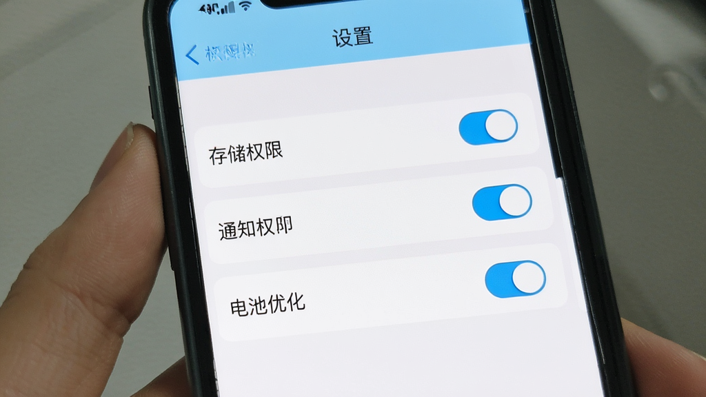 一张展示轻匿提问箱新手设置界面的手机截图风格图片,画面中手机屏幕显示权限设置页面,有存储权限、通知权限、电池优化三个选项,每个选项旁边有开关按钮,界面风格简洁,色彩以白色和淡蓝色为主,顶部有「设置」标题,画质干净无多余元素
