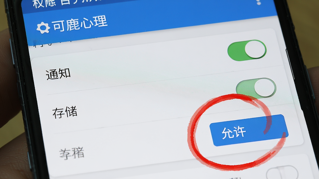 一部安卓手机屏幕特写,显示着“可鹿心理”的权限设置页面,页面上有“通知”、“存储”等开关选项,画面用红色圆圈标注了“允许”按钮,整体风格是教程截图样式,清晰明了,画质干净,文字清晰可辨