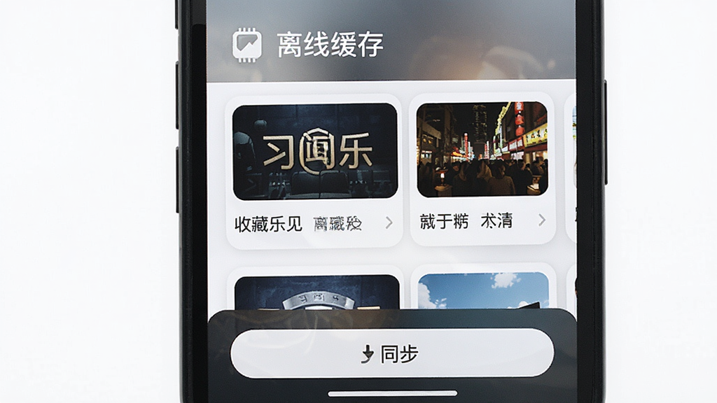 习闻乐见 离线缓存与收藏功能展示 手机屏幕显示收藏夹列表 顶部有离线缓存图标 中间为已缓存文章卡片 底部有同步按钮 风格为清爽卡片式设计 细节图标精致 画质干净无多余元素