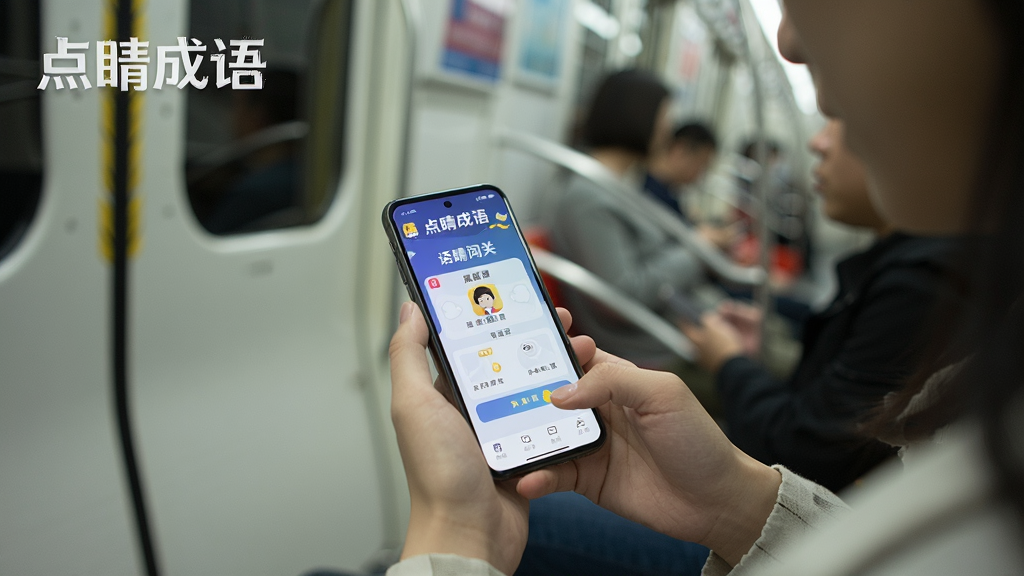 一张展示点睛成语离线使用场景的图片,画面中一个人坐在地铁里拿着手机玩点睛成语,手机屏幕清晰显示成语闯关界面,周围环境简洁,风格生活化,画面中有