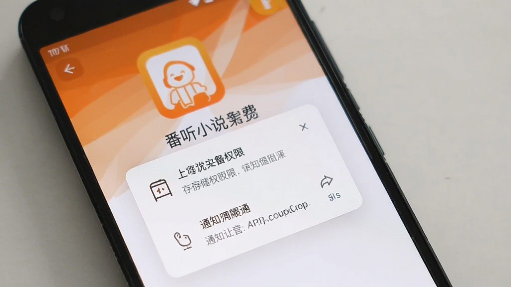 一张展示番听小说免费看APP在安卓手机上安装完成后首次打开权限请求界面的场景图,手机屏幕内显示存储权限和通知权限的弹窗提示,背景是APP启动页,风格简洁,配色以橙色和白色为主,画质干净无多余元素