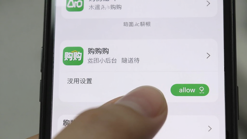 购购 主体是一个手机屏幕特写,布局是设置界面的应用管理页,中间高亮显示购购APP的权限设置选项,排版简洁,风格是真实的手机系统截图风格,细节上手指正在点击允许后台运行按钮,背景虚化,画质清晰,干净,无多余元素