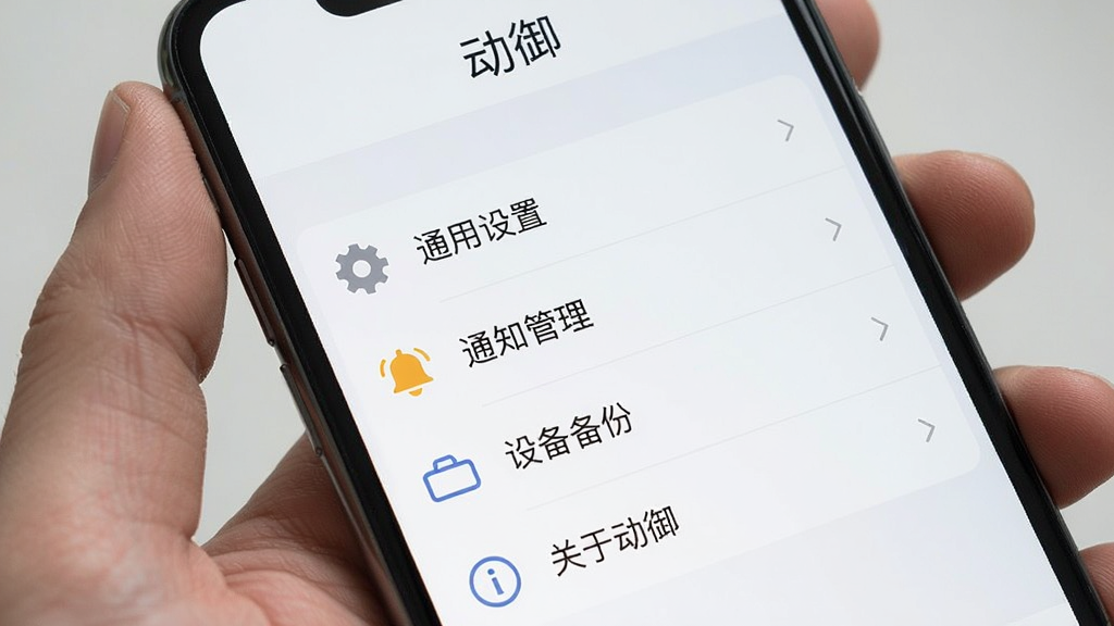 一张展示动御软件设置页面的手机截图,画面中动御App的设置菜单页面,上方显示“动御”文字,下方排列着“通用设置”、“通知管理”、“设备备份”、“关于动御”等选项,每个选项带有简洁的图标,界面采用浅色主题,布局规整,风格极简,画质清晰干净