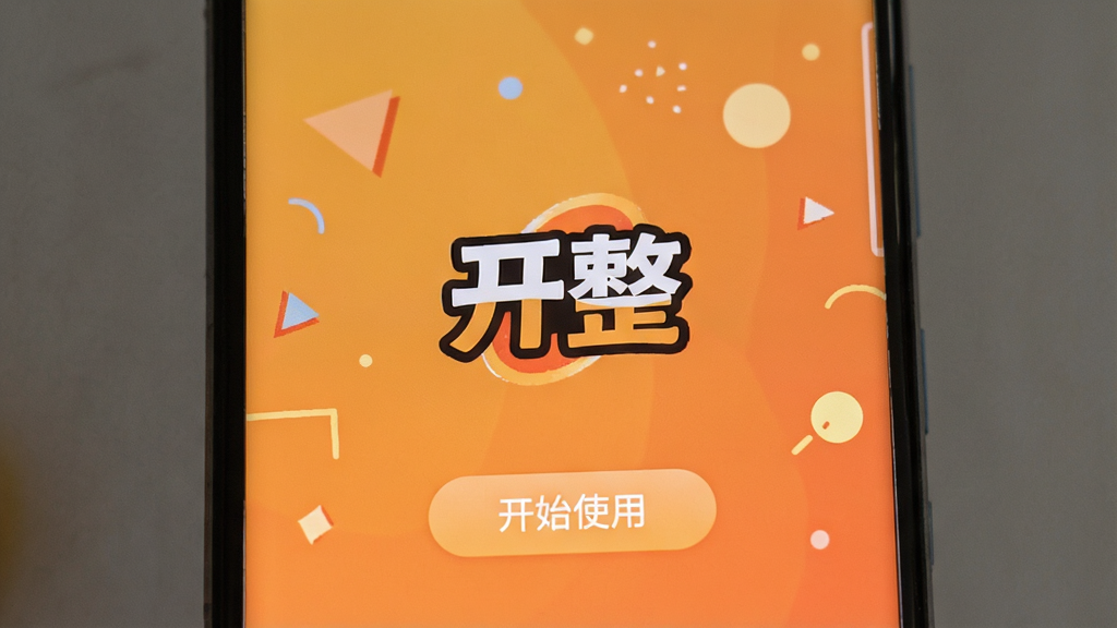 一部安卓手机屏幕显示“开整”应用安装完成后的欢迎界面,屏幕上有“开整”Logo和“开始使用”按钮,背景为温馨的橙色渐变,周围有简单的几何图形装饰,风格友好,布局居中,画质清晰,无多余元素