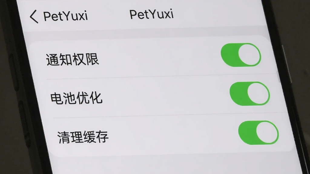 一张手机屏幕截图展示“PetYuxi”的设置页面,页面上有“通知权限”“电池优化”“清理缓存”三个选项开关,开关呈绿色开启状态,界面背景为浅灰色,文字为深灰色,布局清晰,风格简约,画质干净