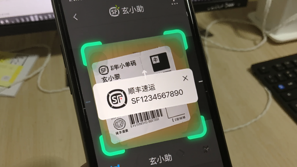 一张“玄小助”应用正在识别快递单号的截图,手机屏幕上显示扫描框对准一个快递面单,识别结果弹出,显示“顺丰速运 SF1234567890”,背景是桌面,整体界面简洁,识别框醒目,画质清晰。