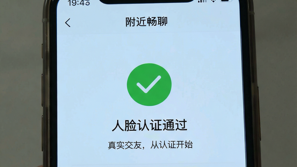 一张手机截图,展示“附近畅聊”的实名认证界面,背景是纯色浅蓝,中间有一个绿色对勾图标,下方文字“人脸认证通过”,配文“真实交友,从认证开始”,界面简洁,细节清晰,画质干净无多余元素