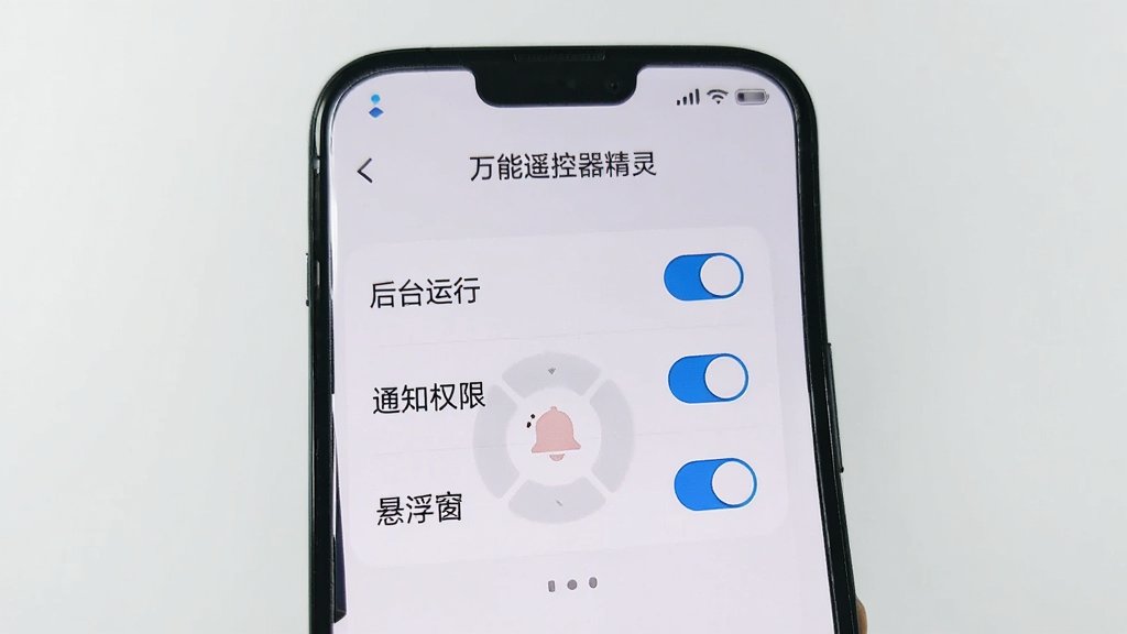 展示手机屏幕上“万能遥控器精灵”的设置页面,有“后台运行”、“通知权限”、“悬浮窗”等选项开关,界面简洁,风格现代,背景干净。
