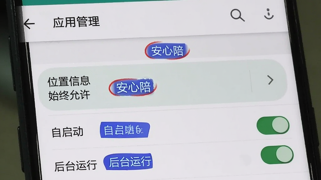 画面展示一部安卓手机的系统设置界面,重点突出“应用管理”中的“安心陪”权限设置页面,页面上“位置信息”权限被高亮显示为“始终允许”,下方还有“自启动”和“后台运行”的开关处于开启状态。界面风格为原生安卓风格,文字清晰,用红色和蓝色小标签标注了关键步骤,整体画质干净,无多余装饰。