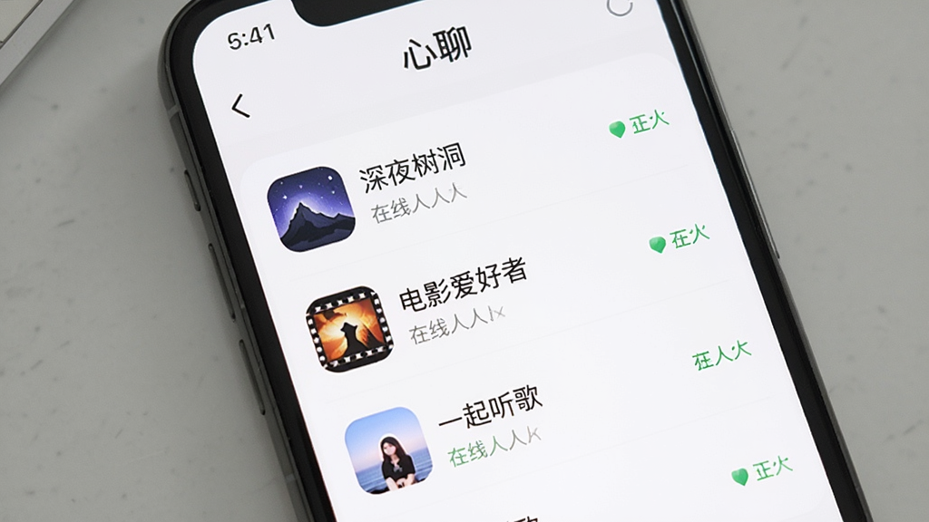 一个手机屏幕界面,展示“心聊”的兴趣群组列表页,可以看到“深夜树洞”、“电影爱好者”、“一起听歌”等群组名称,每个群组旁边有在线人数显示,界面风格清爽干净