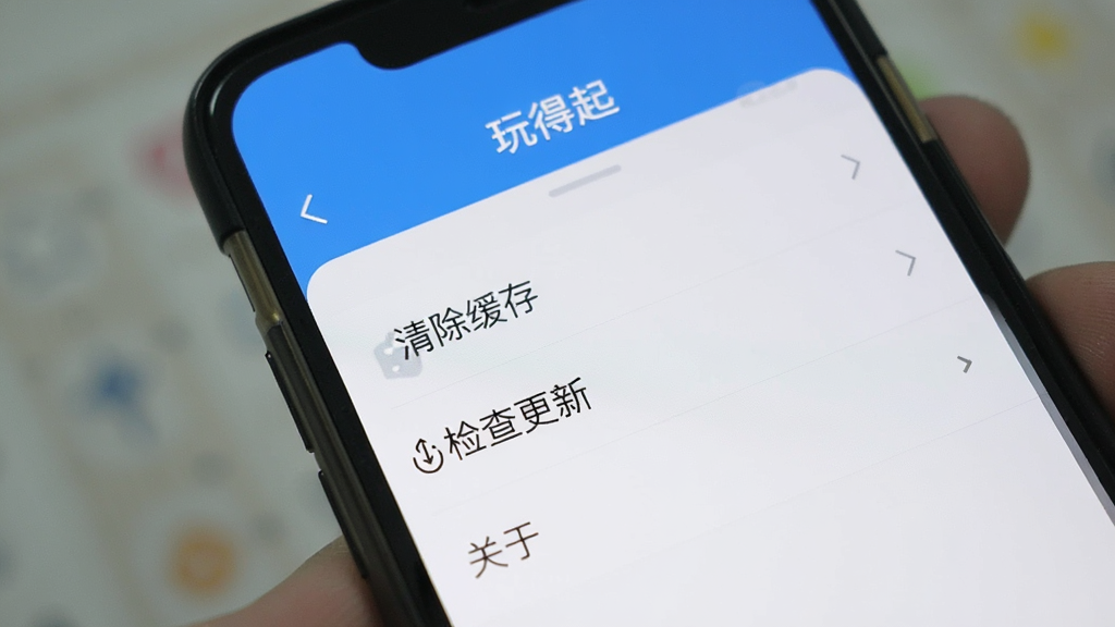 手机屏幕上显示“玩得起”App的设置界面,里面有“清除缓存”“检查更新”“关于”等选项,界面简洁,画质干净无多余元素