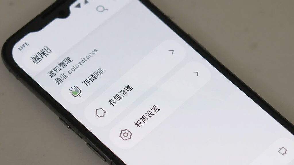 一部安卓手机展示「丝咪」设置界面的生图,屏幕显示通知管理、存储清理、权限设置等选项,界面以白色和浅灰色为主,图标为线性风格,布局清晰,风格简约现代,画质干净,无多余元素