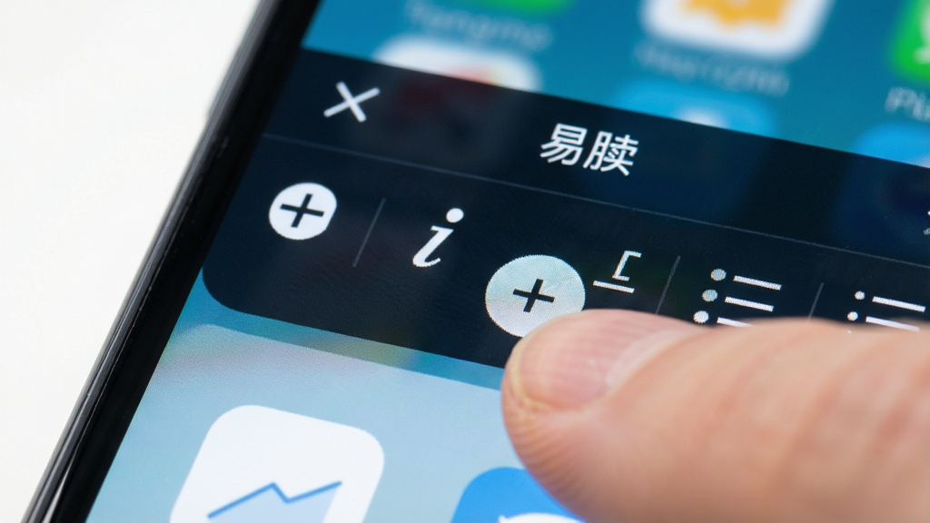手机屏幕特写显示“易牍”编辑工具栏,包含加粗、斜体、下划线、列表等图标,手指正在点击加粗按钮,画面聚焦于屏幕细节,风格清晰明快,画质锐利