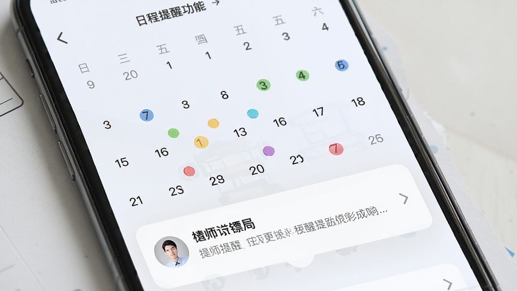 律师镖局 日程提醒功能界面 手机屏幕显示月历视图 日期上有彩色圆点标记不同事项 下方弹出提醒通知卡片 布局层次分明 风格清新简约 细节精致 画质干净 无多余元素