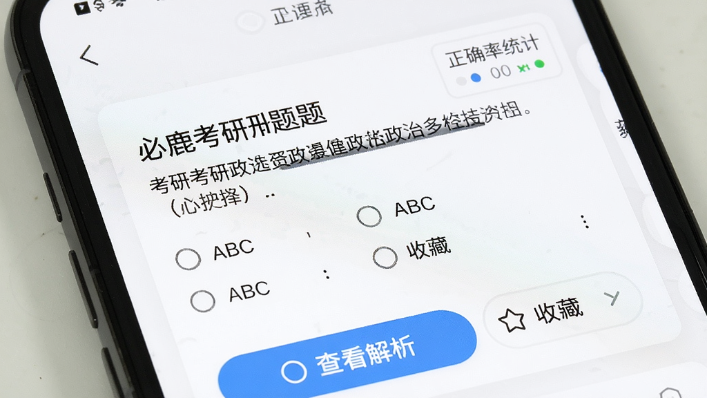 必鹿考研刷题界面特写,手机屏幕显示一道考研政治多选题,题干文字清晰,下方有ABCD四个选项,底部有查看解析按钮和收藏按钮,屏幕右上角显示正确率统计,背景为白色卡片式设计,整体风格清爽干净,画质清晰无杂乱元素。