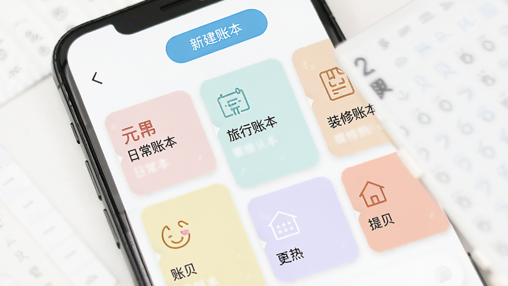 元贝贝多账本管理界面展示,手机屏幕显示多个账本卡片排列,每个卡片有不同图标和名称如日常账本、旅行账本、装修账本,卡片采用柔和色彩区分,背景为白色,顶部有新建账本按钮,界面布局整齐有序,风格简约清新,画质干净高清