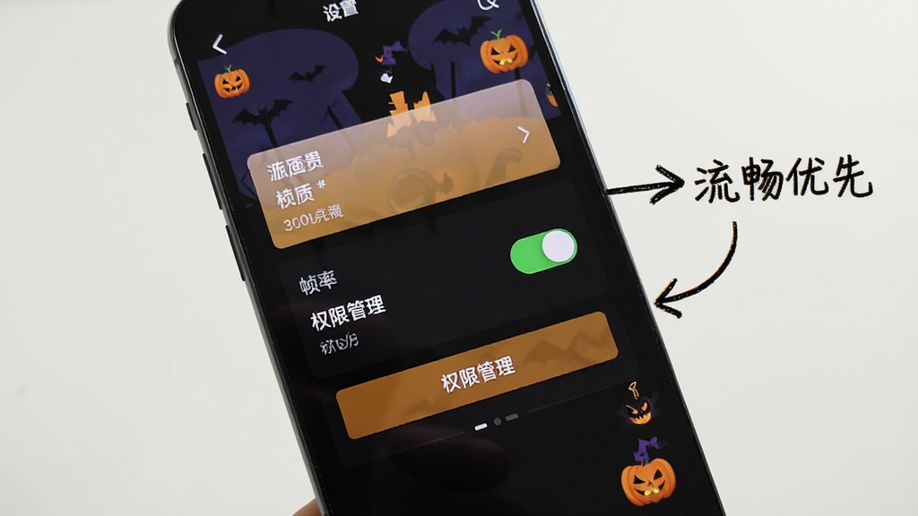 手机屏幕显示游戏设置界面,画质选项、帧率开关、权限管理按钮清晰可见,旁边有手绘风格箭头标注“流畅优先”,万圣节小图标点缀,画面干净,无多余元素
