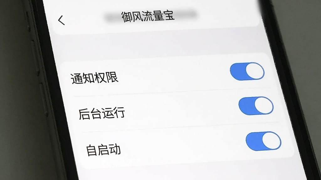 一张手机屏幕录制截图风格的图片,展示“御风流量宝”的权限设置引导页面,页面上有“通知权限”“后台运行”“自启动”等选项开关,开关旁边有蓝色对勾标记,背景是简洁的白色设置界面,风格清晰明了,画质干净无多余元素