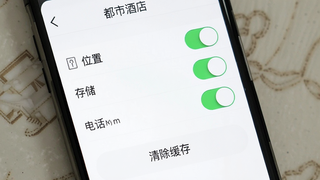手机屏幕上显示“都市酒店”的权限设置界面,有位置、存储、电话等权限开关,下方有“清除缓存”按钮,界面背景为白色,文字清晰,布局规整,风格简洁,画质干净,无多余元素