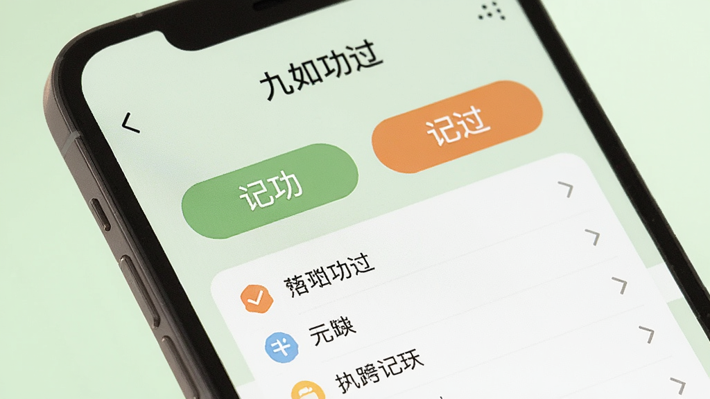 一张手机屏幕特写图,画面中显示“九如功过”应用的记录页面,屏幕中央有两个明显的按钮分别写着“记功”和“记过”,按钮下方是已经记录好的几条条目,每条前面有小图标区分,背景是柔和的浅绿色,整体风格温馨治愈,画质干净,无多余元素